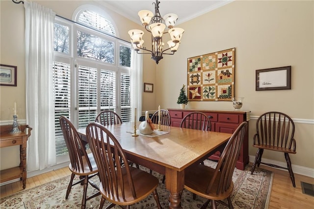 dining room featuring ornamental molding, an inviting chandelier, and light hardwood / wood-style floors