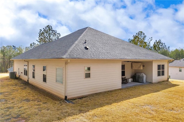 back of property featuring a patio, cooling unit, a lawn, and roof with shingles