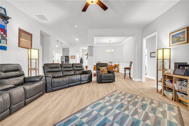 living area with ceiling fan with notable chandelier, visible vents, light wood finished floors, and baseboards