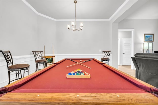 recreation room with pool table, ornamental molding, wainscoting, wood finished floors, and a notable chandelier