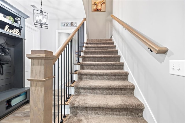 staircase with a chandelier and wood finished floors