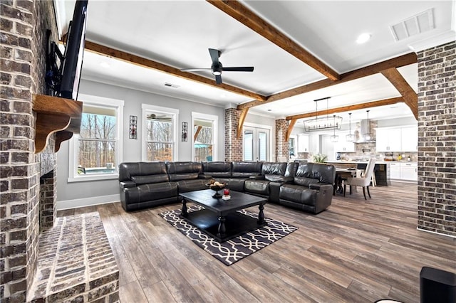 living area featuring a fireplace, visible vents, beam ceiling, and wood finished floors