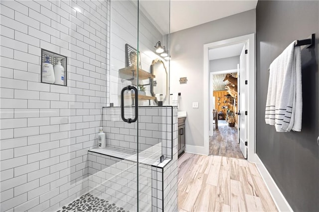 bathroom featuring a stall shower, wood finished floors, vanity, and baseboards