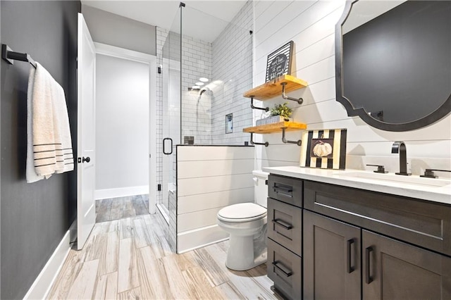 full bath featuring toilet, a stall shower, vanity, wood finished floors, and baseboards