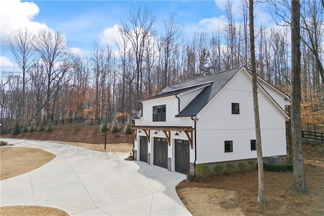 view of front of property with a garage, a shingled roof, fence, and concrete driveway