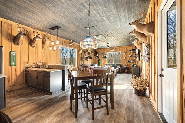 dining area featuring dark wood-style floors, wood ceiling, visible vents, and wood walls