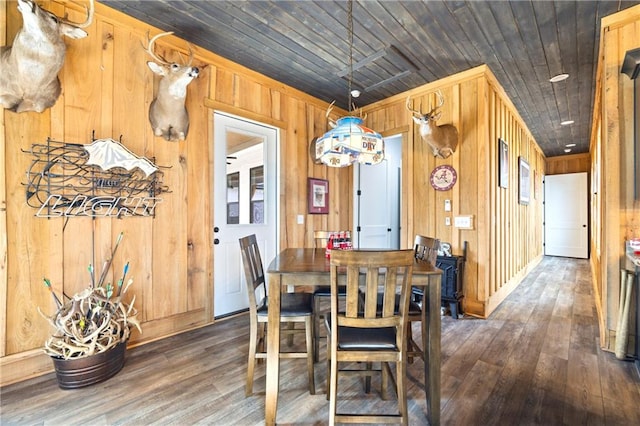 dining space with wooden ceiling, dark wood-type flooring, and wood walls