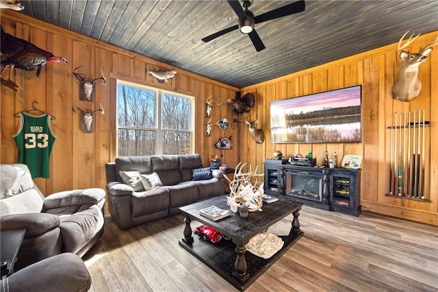 living area with a fireplace, wooden ceiling, wood finished floors, and wooden walls