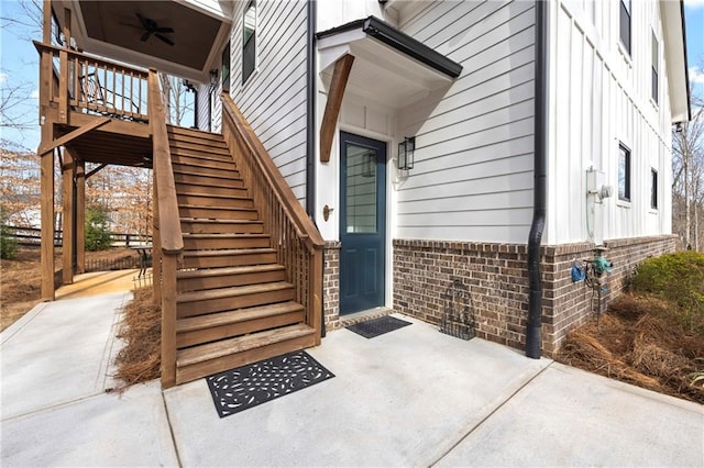 view of exterior entry with a ceiling fan and brick siding