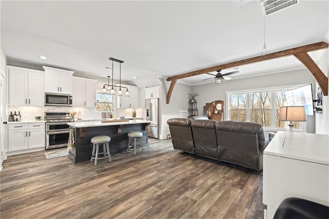 kitchen featuring stainless steel appliances, a kitchen island, white cabinetry, light countertops, and decorative light fixtures