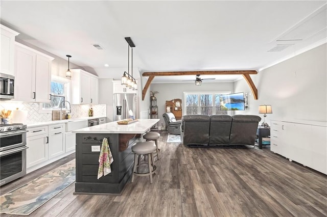 kitchen featuring white cabinets, stainless steel appliances, light countertops, and a center island