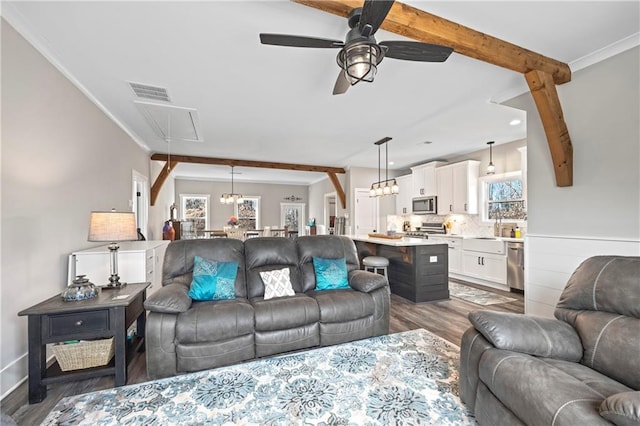 living area with attic access, visible vents, dark wood finished floors, a ceiling fan, and beamed ceiling