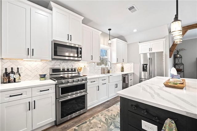 kitchen with pendant lighting, visible vents, appliances with stainless steel finishes, white cabinetry, and a sink