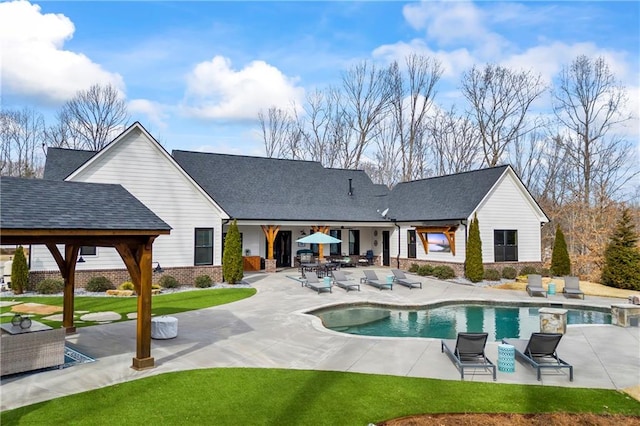 back of property featuring brick siding, a yard, a gazebo, an outdoor pool, and a patio area