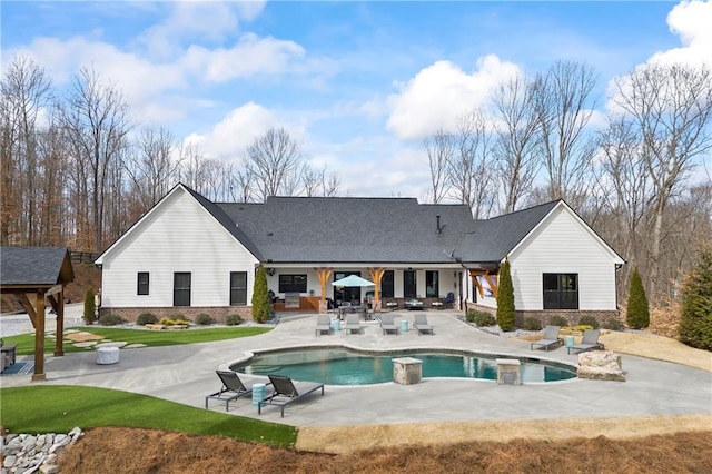 rear view of house with an outdoor pool, brick siding, and a patio