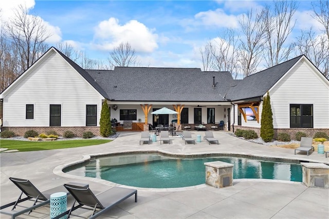 back of house with brick siding, an outdoor pool, and a patio