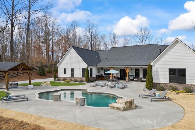 rear view of house featuring brick siding, an outdoor pool, a patio, and a gazebo