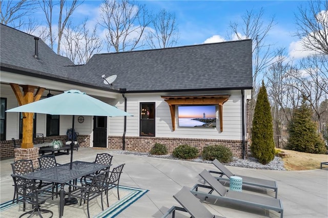 exterior space with brick siding, a patio area, an outdoor living space, and a shingled roof