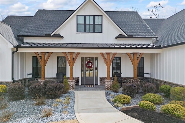 property entrance featuring a shingled roof, a standing seam roof, a porch, board and batten siding, and brick siding