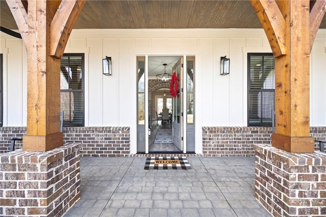 entrance to property featuring a porch and brick siding