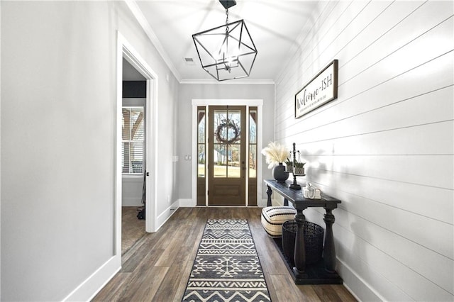 doorway with dark wood finished floors, visible vents, ornamental molding, a chandelier, and baseboards