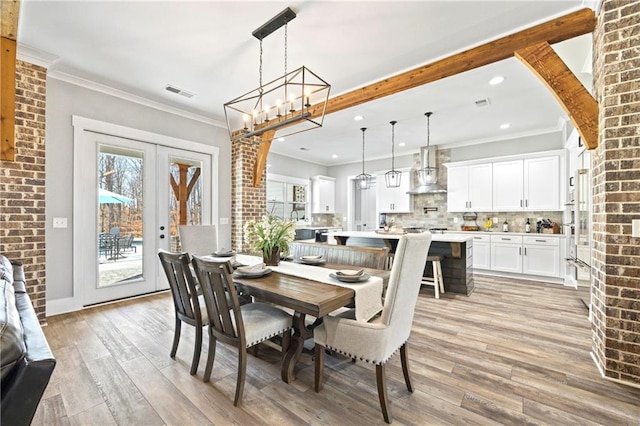 dining room with ornamental molding, french doors, visible vents, and light wood-style floors