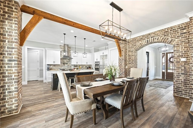 dining room with brick wall, arched walkways, and wood finished floors