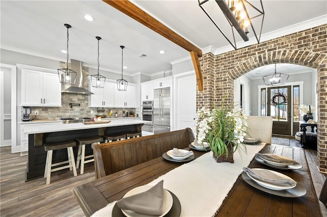 dining room featuring arched walkways, dark wood-style flooring, an inviting chandelier, crown molding, and beam ceiling