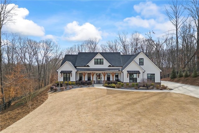 modern farmhouse with driveway, metal roof, a standing seam roof, covered porch, and a front yard