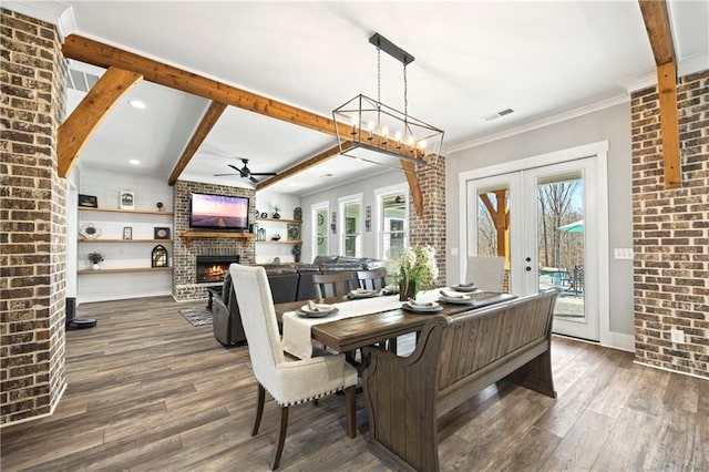 dining area featuring a brick fireplace, visible vents, dark wood-type flooring, and beamed ceiling