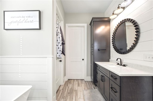 bathroom featuring a freestanding tub, vanity, and wood finished floors