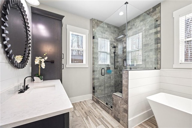 full bath with wood finished floors, a stall shower, a freestanding tub, and vanity