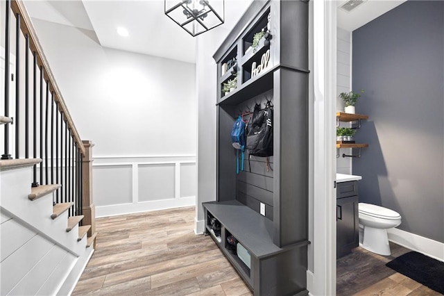 mudroom with light wood-style floors, visible vents, a decorative wall, and baseboards