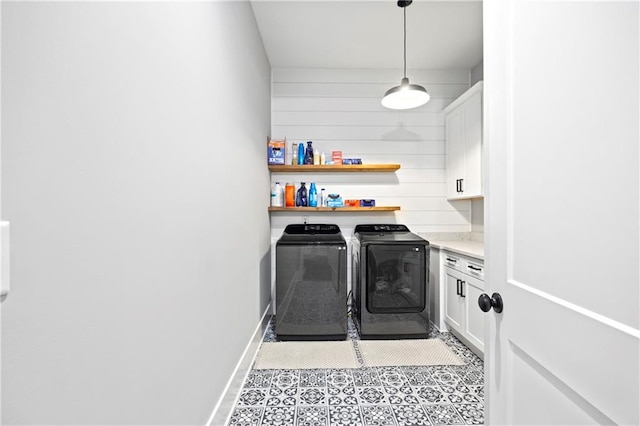 laundry area featuring cabinet space, light tile patterned floors, wooden walls, baseboards, and washing machine and dryer