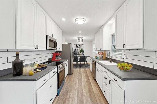 1573 Deerwood Ln, Acworth, GA 30102 - kitchen with white cabinets, sink, light wood-type flooring, appliances with stainless steel finishes, and tasteful backsplash