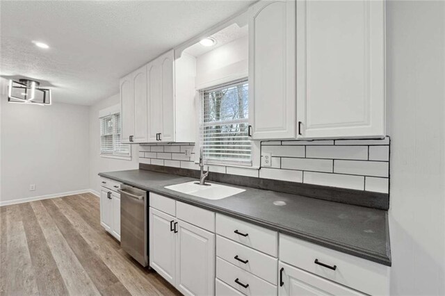 1573 Deerwood Ln, Acworth, GA 30102 - kitchen featuring decorative backsplash, light wood-type flooring, stainless steel dishwasher, sink, and white cabinets