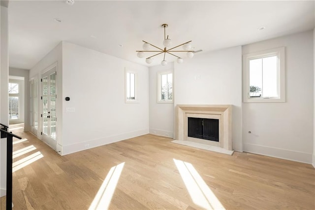 unfurnished living room featuring a notable chandelier and light wood-type flooring