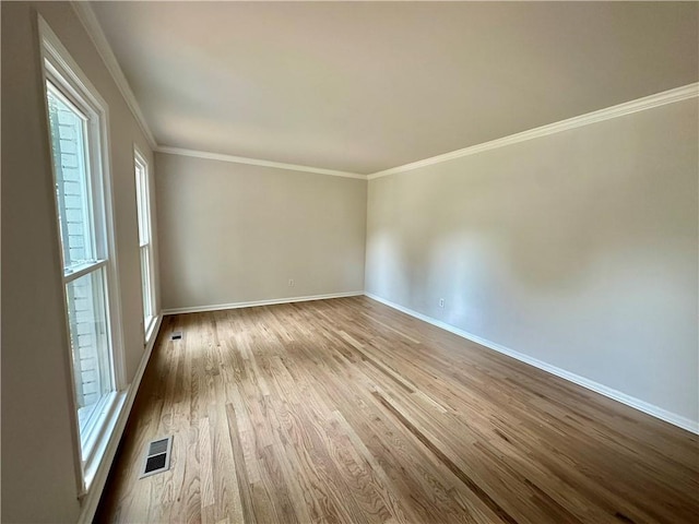 empty room featuring ornamental molding, visible vents, baseboards, and wood finished floors