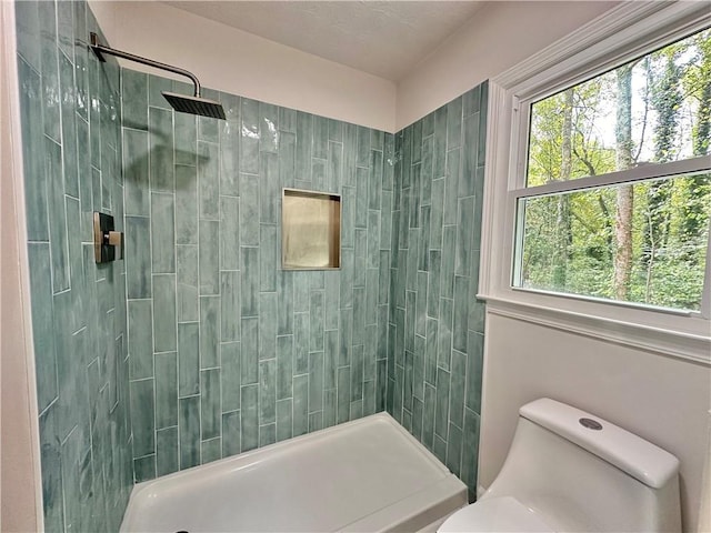 bathroom with tiled shower and toilet