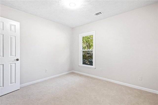 spare room featuring baseboards, visible vents, and light colored carpet