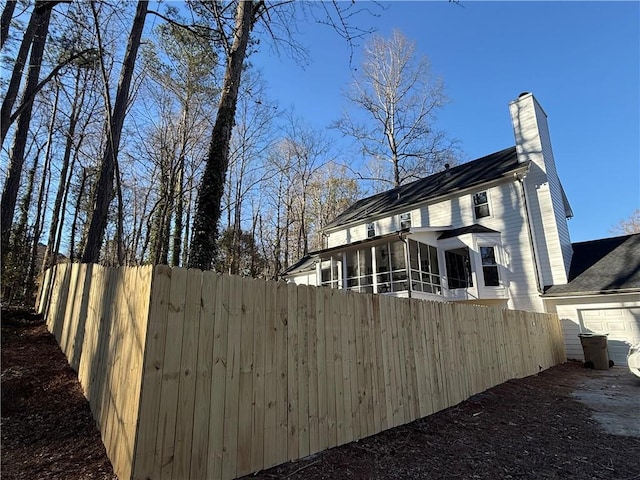 view of property exterior with a sunroom, fence, and a chimney