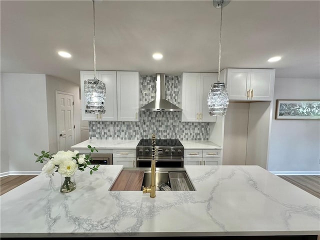 kitchen featuring pendant lighting, white cabinetry, stainless steel range, and wall chimney range hood