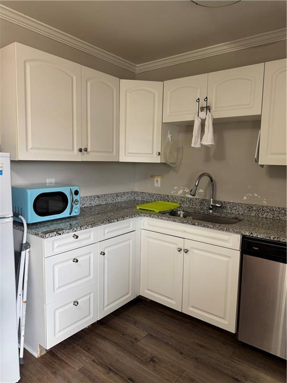 kitchen with sink, dishwasher, dark hardwood / wood-style floors, white cabinets, and dark stone counters