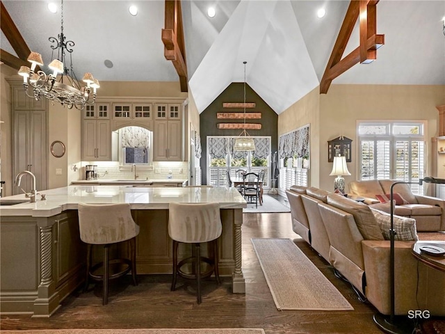 kitchen with glass insert cabinets, open floor plan, an inviting chandelier, cream cabinets, and a large island with sink