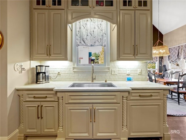 kitchen with cream cabinets, glass insert cabinets, pendant lighting, and a sink