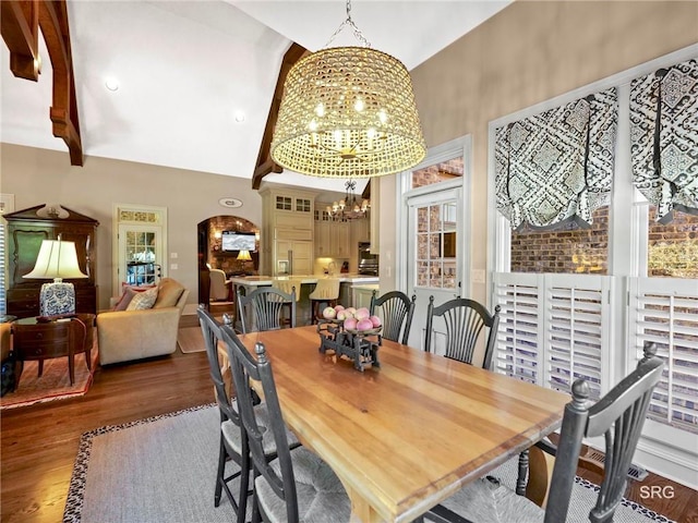 dining space with high vaulted ceiling, dark wood-type flooring, and an inviting chandelier