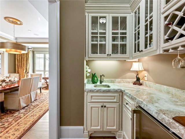 bar featuring indoor wet bar, a sink, light wood-style flooring, and dishwasher