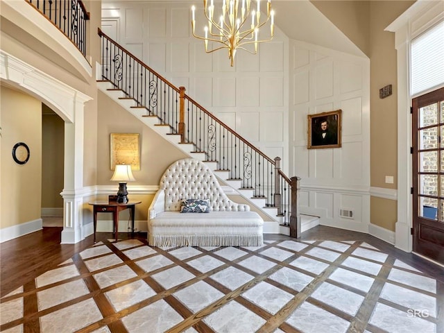 foyer entrance featuring visible vents, a high ceiling, baseboards, and a decorative wall