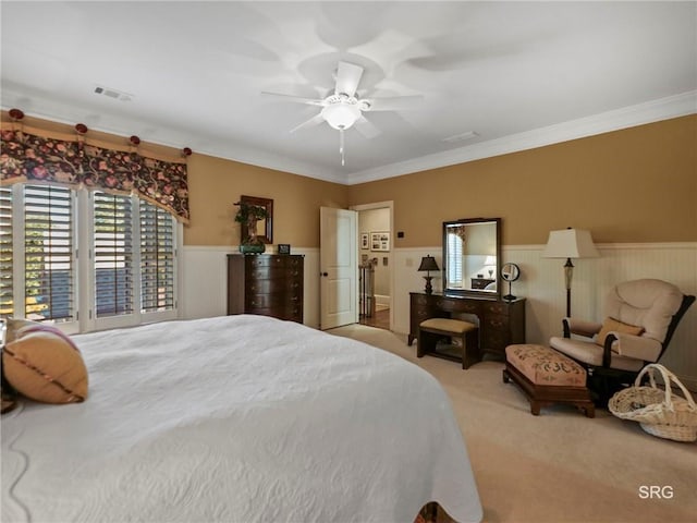 bedroom featuring light carpet, visible vents, crown molding, and wainscoting