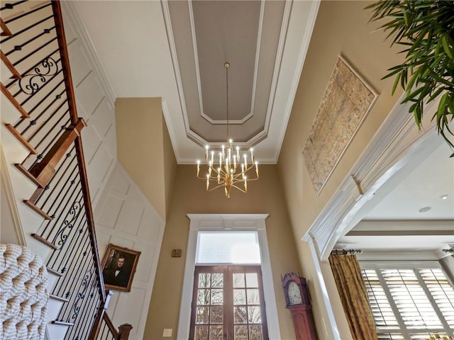 entrance foyer with stairs, ornamental molding, a notable chandelier, and french doors